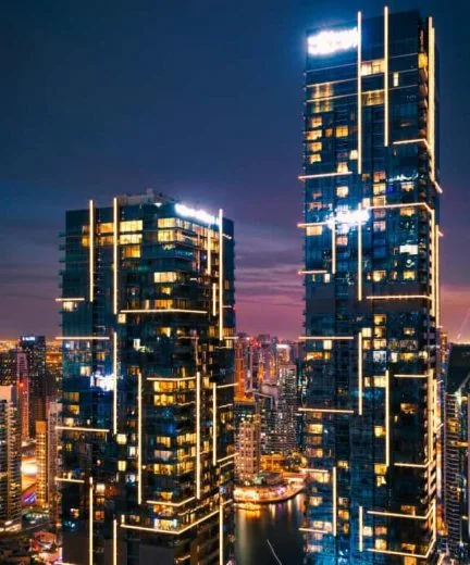 A nighttime cityscape featuring two tall, modern skyscrapers